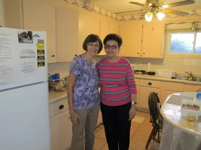 two women standing in a kitchen next to a table at Rainbow Bed & Breakfast in Niagara Falls