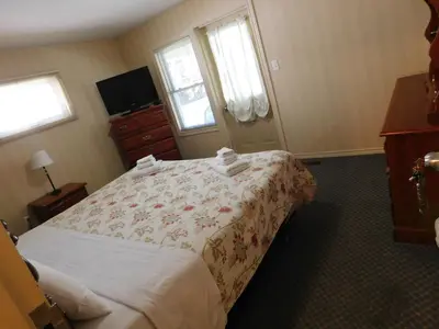a bedroom with a bed and a dresser and windows at Rainbow Bed & Breakfast in Niagara Falls