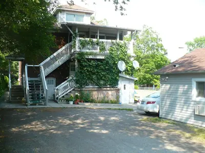 a house with a staircase and a car parked in front of it at Rainbow Bed & Breakfast in Niagara Falls