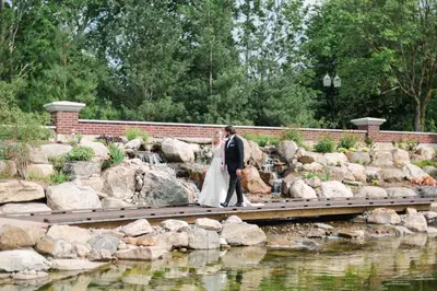 a bride and groom walking on a bridge over a pond at Pillar and Post Inn & Spa in Niagara on the Lake