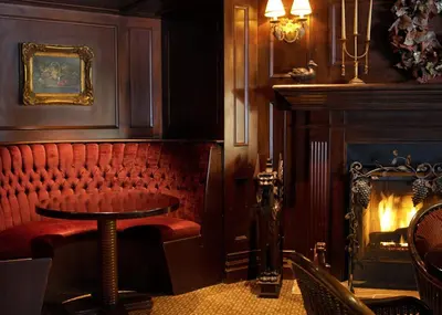 a red booth in a restaurant with a fire place at Queens Landing in Niagara on the Lake