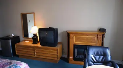 a room with a tv on a wooden dresser and a bed at Kings Inn Near the Falls in Niagara Falls