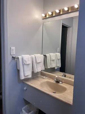 a bathroom with a sink and a mirror and towels at Knights Inn - Park Villa Motel, Midland in Midland