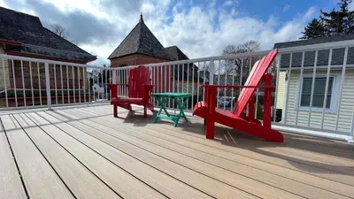 a deck with two red chairs and a green table at Bedham Hall B&B in Niagara Falls