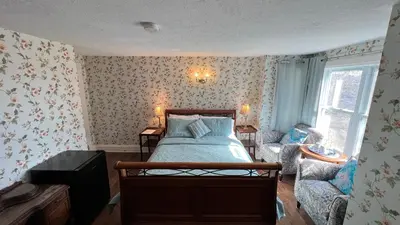 a bedroom with a bed and a chair and a window at Bedham Hall B&B in Niagara Falls