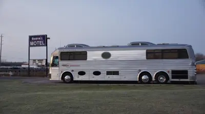 a silver bus parked next to a motel sign at Robyn's Motel in Peterborough