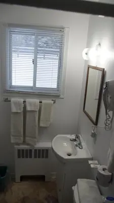 a white bathroom with a sink and a window at Robyn's Motel in Peterborough