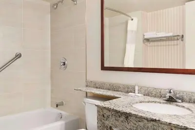a bathroom with a sink and a tub and a mirror at Travelodge by Wyndham Owen Sound ON in Owen Sound