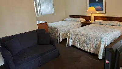 a hotel room with two beds and a chair at Wasaga Beach Inn And Cottages in Wasaga Beach