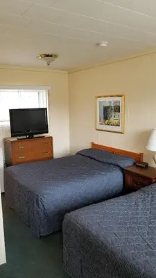 a hotel room with two beds and a flat screen tv at Wasaga Beach Inn And Cottages in Wasaga Beach