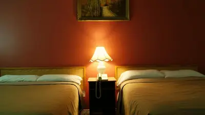 two beds in a room with a lamp on a table at Blue Jay Motel in Peterborough