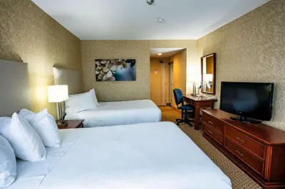 a hotel room with two beds and a flat screen tv at Best Western Voyageur Place Hotel in Newmarket