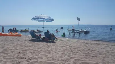 a group of people on a beach with an umbrella at SunPort Beach Resort in Balm Beach
