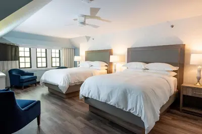 a bedroom with two beds and a blue chair at The Glenerin Inn in Mississauga