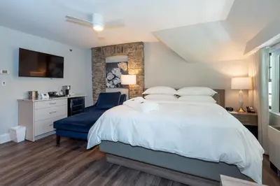a bedroom with a large bed and a blue chair at The Glenerin Inn in Mississauga