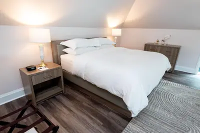 a bedroom with a large white bed and a chair at The Glenerin Inn in Mississauga