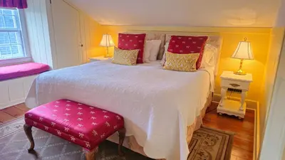 a bedroom with a large white bed with red pillows at Historic Wilson-Guy House in Niagara on the Lake