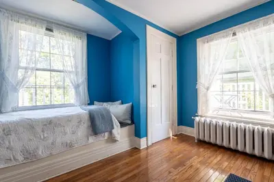 a blue bedroom with a bed and two windows at Chestnut Inn in Niagara Falls