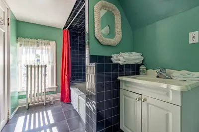 a bathroom with green walls and a sink and a tub at Chestnut Inn in Niagara Falls