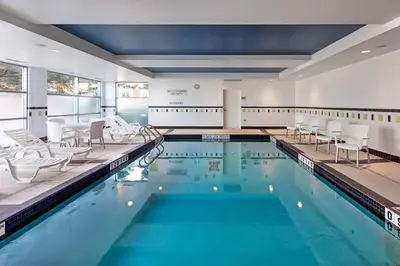 a swimming pool with white chairs and tables and chairs at Fairfield Inn & Suites by Marriott Toronto Mississauga in Mississauga