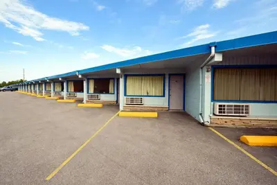 a row of buildings with yellow benches in a parking lot at Travelers Inn in Belleville