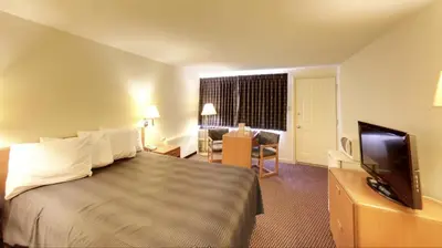 a hotel room with a bed and a flat screen tv at Travelers Inn in Belleville