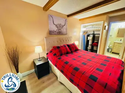 a bedroom with a bed with a red checkered blanket at Rustic Mountainside Chalet in Blue Mountains