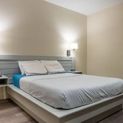 a bedroom with a white bed with a blue blanket at Leelas Villa Inn Flesherton in Flesherton