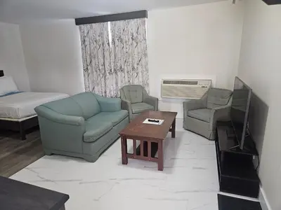 a living room with a couch and two chairs and a television at Leelas Villa Inn Flesherton in Flesherton