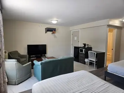 a bedroom with a living room with a couch and a television at Leelas Villa Inn Flesherton in Flesherton