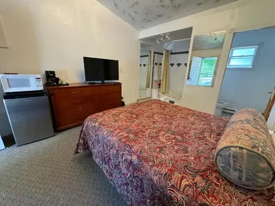 a bedroom with a bed and a flat screen tv at Holiday Motel in Orillia