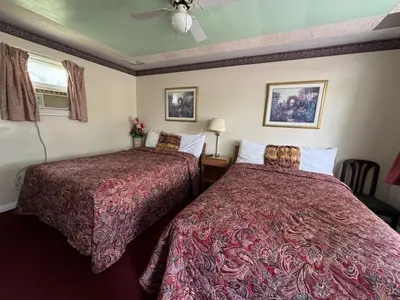 a hotel room with two beds and a ceiling fan at Holiday Motel in Orillia