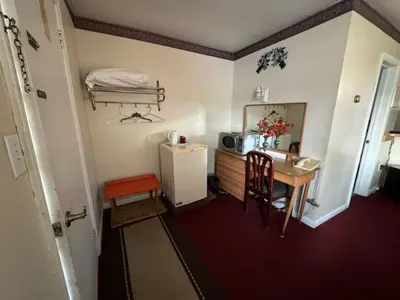a small room with a table and a small refrigerator at Holiday Motel in Orillia