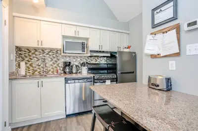 a kitchen with white cabinets and a granite counter top at Blue Mountain Studio Loft at North Creek Resort in Blue Mountains