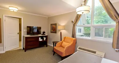 a room with a chair and a tv and a window at Elm Hurst Inn & Spa in Ingersoll