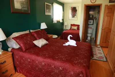 a bedroom with a red bed with a white swan on it at A Garden Stroll Bed & Breakfast in Stratford