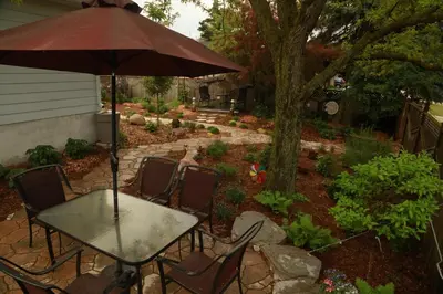 a patio with a table and chairs with an umbrella at A Garden Stroll Bed & Breakfast in Stratford
