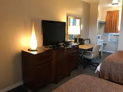a hotel room with a television on a dresser with a desk at Cardinal Court Motel in Saint Thomas