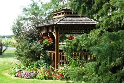a wooden gazebo with flowers in a garden at Stratford Suburban Motel in Stratford