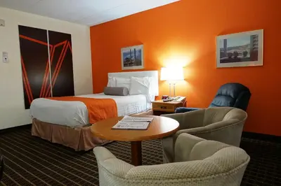 a hotel room with a bed and chairs and a table at Howard Johnson by Wyndham Tillsonburg in Tillsonburg