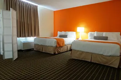 two beds in a hotel room with orange walls at Howard Johnson by Wyndham Tillsonburg in Tillsonburg