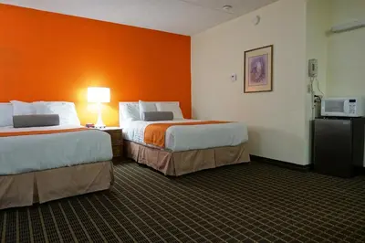 two beds in a hotel room with an orange wall at Howard Johnson by Wyndham Tillsonburg in Tillsonburg