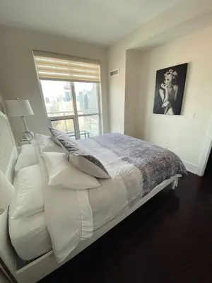 a bedroom with a bed with white pillows and a window at Luxury condo on CN TOWER in Toronto