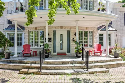 a house with two red chairs on a porch at Somerset - A Private Retreat in Niagara on the Lake