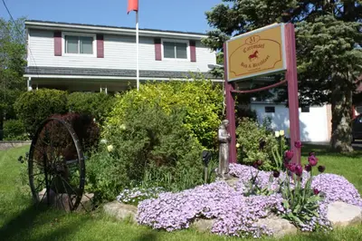 a garden with a sign and flowers in front of a house at Carrousel Bed & Breakfast in Cayuga
