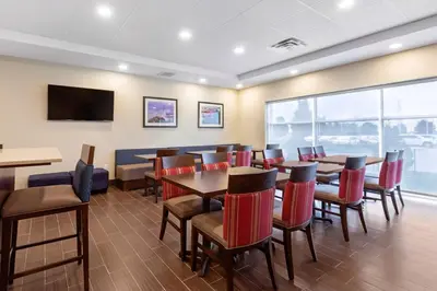 a restaurant with tables and chairs and a flat screen tv at Comfort Inn & Suites in Bowmanville