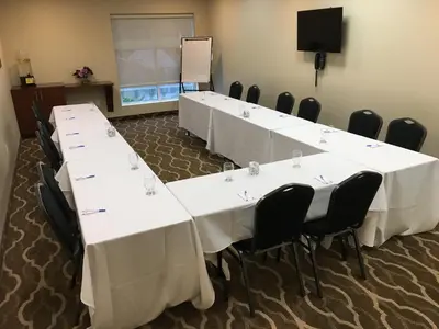 a conference room with white tables and chairs and a screen at Comfort Inn & Suites in Bowmanville