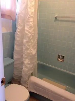 a bathroom with a toilet and a tub with a shower curtain at Lotus Motel in Cobourg