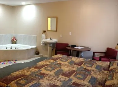 a bedroom with a bed and a sink and a tub at Lotus Motel in Cobourg