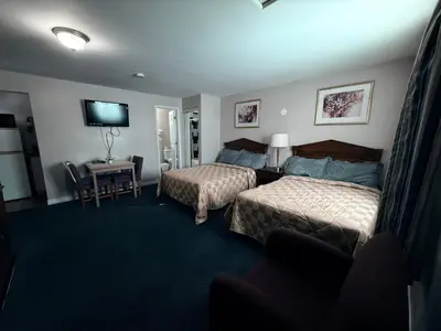 a hotel room with two beds and a television at Guest Inn Motel in Trenton